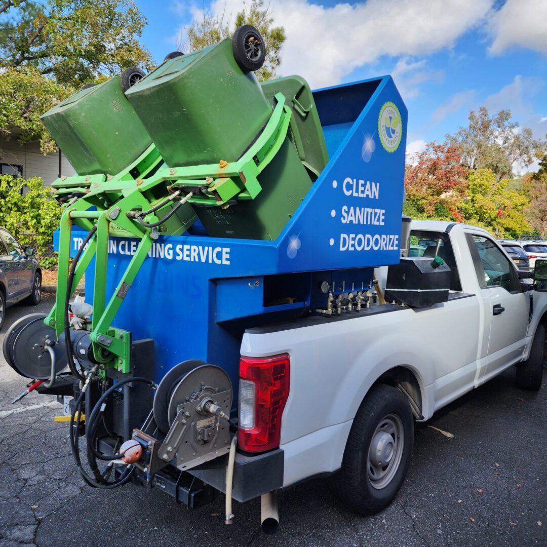 A truck with two green trash cans in the back.